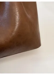 Close-up detail of smooth brown leather texture with minimalist matte finish for tote bag