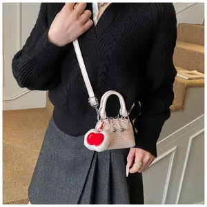 Detail einer rosa gepunkteten Mini-Umhängetasche mit Herz-Anhänger und silberner Kette