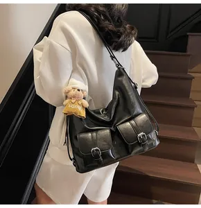 Detail der schwarzen matten PU-Hobo-Tasche mit zwei Vordertaschen und Bärenanhänger