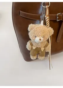 Detail of cute plush bear charm with fashion overalls attached to a brown tote bag