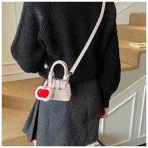 Rosafarbene Muschel-Handtasche mit Perlenkette und Kirsch-Anhänger am Modell