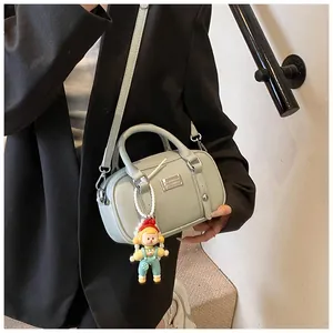 Detail van lichtgroene Boston tas met litchi textuur en een schattige pop hanger