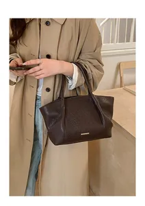 Détail du sac cabas marron foncé en cuir froissé avec une plaque logo en métal doré