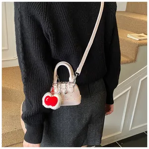 Detail der rosa gepunkteten Muscheltasche mit einem weichen weißen Plüschherz-Kirsch-Anhänger