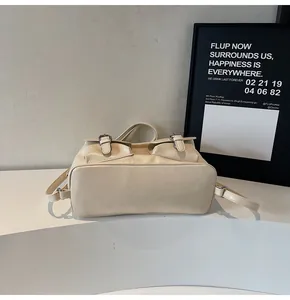 Detail der cremefarbenen Kunstledertasche mit zwei Vordertaschen und Metallschnallen
