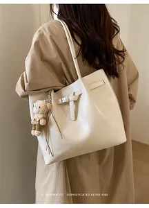 Detailed back view of a minimalist cream tote bag with cute bear charm and belt buckle