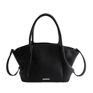 Sac fourre-tout minimaliste en cuir noir de forme ailée avec plaque métallique argentée
