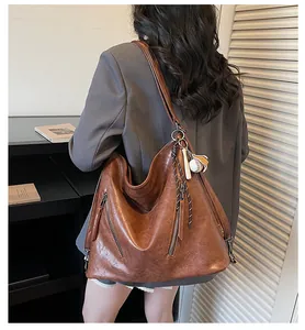 Brown large capacity PU leather tote bag with baseball pendant shown on a model in a grey suit