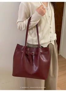 Close-up of minimalist burgundy leather tote bag with elegant metal buckle detail