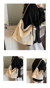 Detail view of a large beige PU leather tote bag with baseball charm and metallic zipper