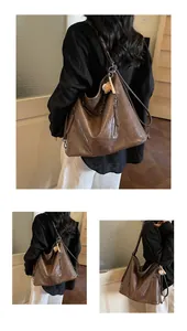 Detail of a large brown vintage faux leather tote bag with side zippers and doll pendant