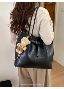 Detail of black leather tote bag with a cute bear charm for a retro office commuter style