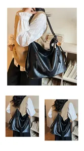 Close-up of black leather hobo bag with zip pockets and baseball glove keychain