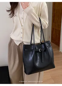 Minimalist black tote bag with silver buckle detail worn on model side profile