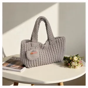 Detail of grey knitted tote bag featuring a striped texture and Hand Made leather label