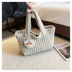 Detail of hand-made knitted tote bag with textured knit pattern and leather label