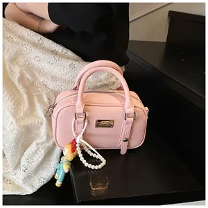 Roze Boston-tas met lycheestructuur, cartoonpopje en een parelketting
