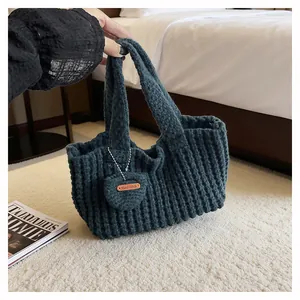 Detail of navy knit tote bag featuring wavy texture, heart charm and Hand Made leather tag