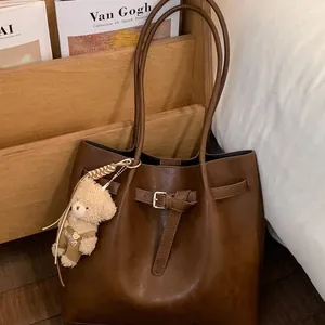 Dark brown retro leather tote bag with a cute bear charm for daily commuting style