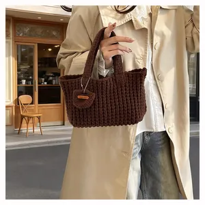 Detail of coffee brown hand-knitted tote bag with thick yarn texture and wooden tag