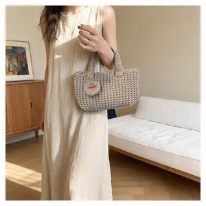 Detail of a beige knit handbag with a small round pouch and Hand Made leather label