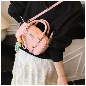 Detail van roze handtas met lycheestuctuur, zilveren plaat en poppenhanger