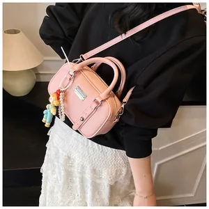 Roze Boston-tas met lychee-textuur, parelhanger en popje gedragen door model
