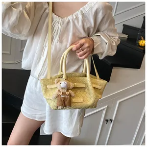 Détail d'un sac seau tissé jaune avec un charmant ours en peluche et une bandoulière fine