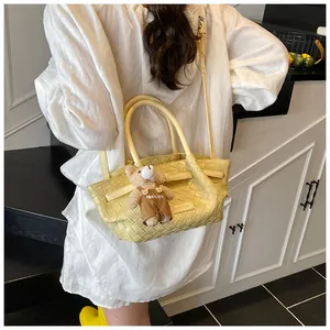 Détail du sac seau en cuir tressé jaune clair avec charm ours brun porté par le mannequin
