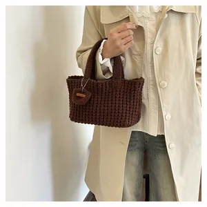 Close-up of dark brown chunky knit handbag featuring waffle texture and Hand Made label