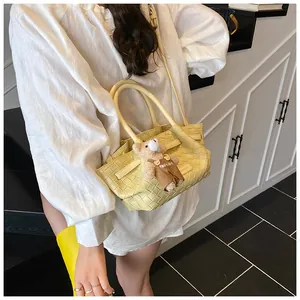 Détail du sac seau tissé jaune clair avec un adorable charm en peluche d'ours marron