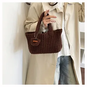 Close-up of dark brown hand-woven knit handbag with handmade wooden tag detail
