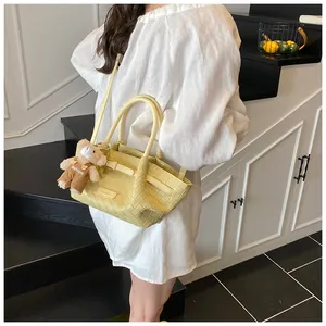 Détail du sac seau tissé jaune avec breloque ours en peluche et bandoulière réglable