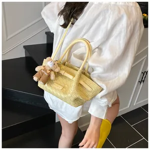 Détail du sac seau tressé crème avec un charm ours mignon et le logo de la marque