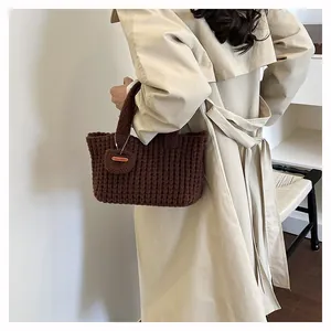Close-up of hand-made dark brown woven knit handbag with textured pattern and decorative tag