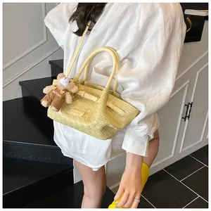 Détail du sac seau tissé jaune avec plaque de marque et charmant porte-clés ours