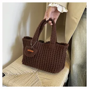 Detail of hand-knitted brown tote bag with leather 'Hand Made' label on texture