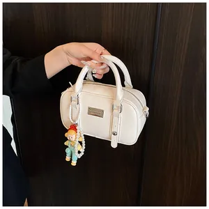 Detail van witte Boston-tas van generfd leer met cartoonpop en parelketting hanger