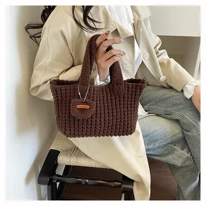 Detail of a brown hand-knit tote bag featuring a round charm with a Hand Made leather label