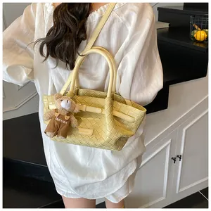 Détail d'un sac seau tissé jaune clair avec poignées et breloque ours mignon