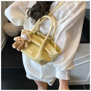 Détail du sac seau tressé crème avec poignée ronde et pendentif ourson en peluche