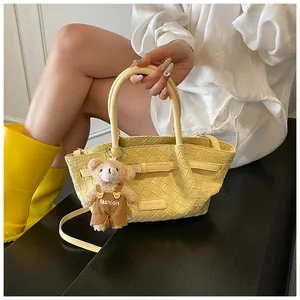 Détail d'un sac seau tissé avec pendentif en peluche d'ours et étiquette de marque