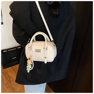 Close-up van beige lederen handtas met parelhanger gedragen door een model