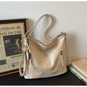 Off-white leather tote bag with double zipper pockets and baseball charm accessory