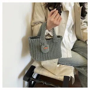 Detailed macro of dark grey knit handbag featuring a heart charm with Hand Made label