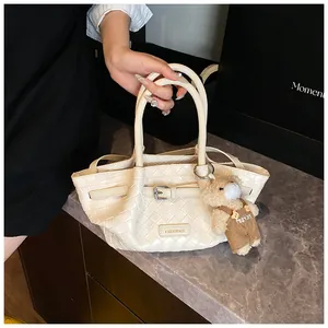Détail du sac seau tressé beige avec boucle en métal et charm d'ours décoratif
