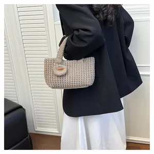 Close-up of oatmeal knit handbag with waffle texture and Hand Made leather tag detail