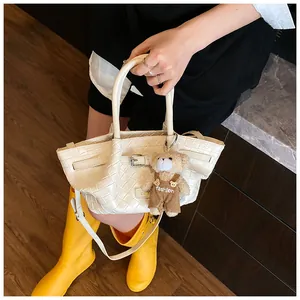 Détail du sac seau blanc tressé avec boucle en cuir et pendentif ours en peluche