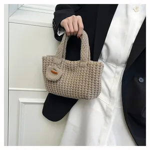 Detail of hand-woven texture and heart pendant on a beige knit wrist bag
