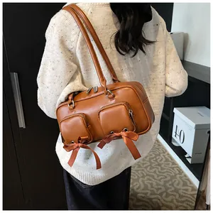 Detailed view of brown leather tote featuring two small zip pockets and satin bows
